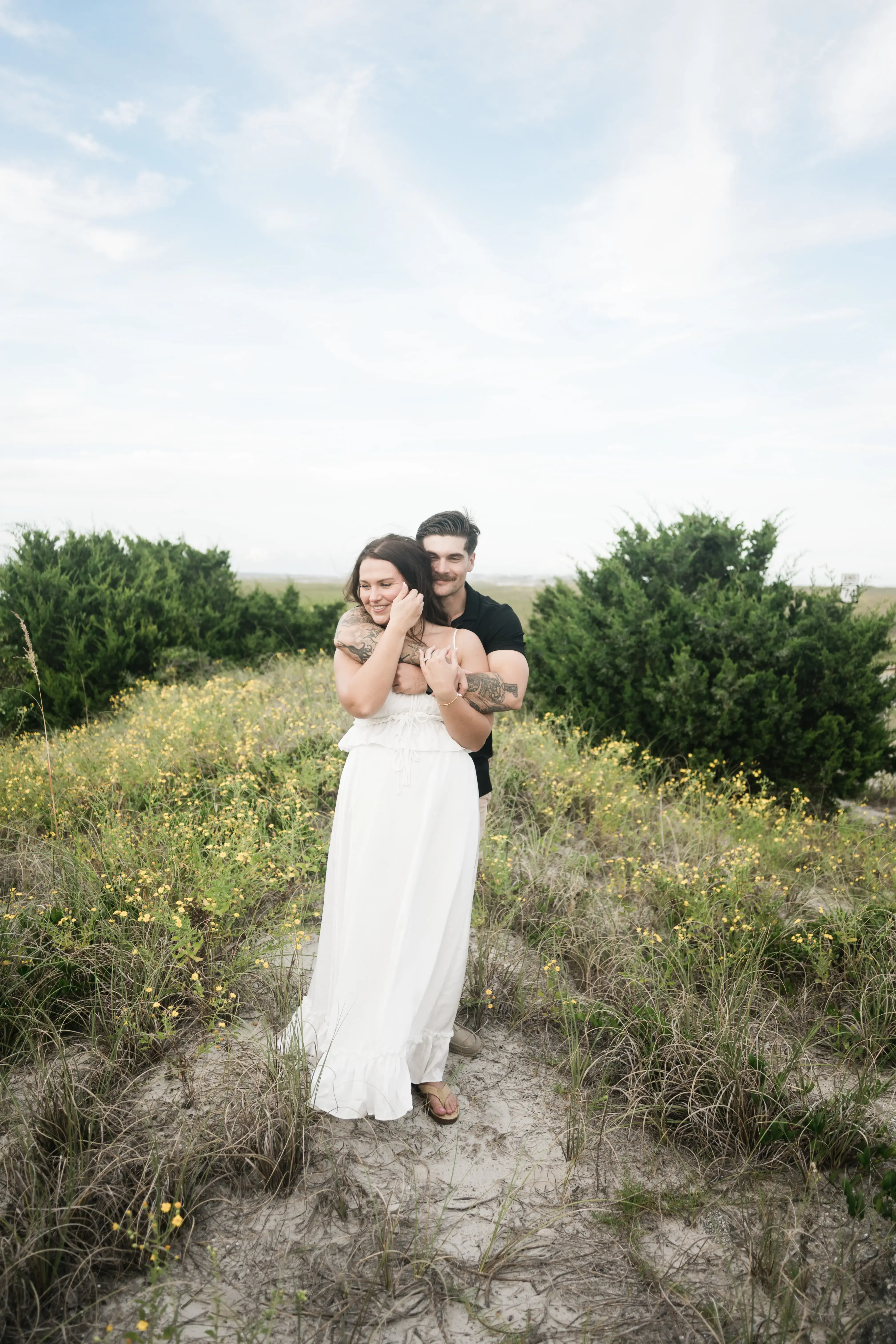 Environmental couple portrait on windswept beach with dunes and natural light